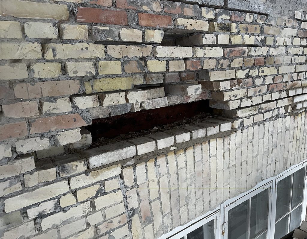 Ældre facade hvor hård cementfuge står intakt, mens de blødere mursten omkring er frostsprængte og skallet af, fordi fugen er hårdere end stenen