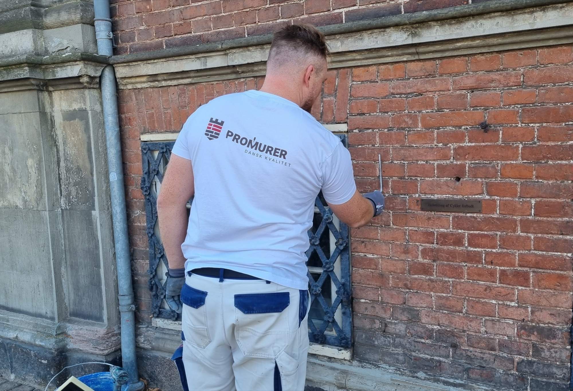Murer fra Promurer undersøger revner og frostskader i en gammel teglstensfacade før renovering