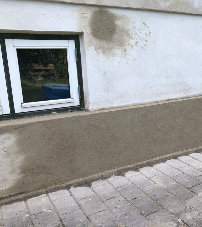 Nypudset sokkel langs bunden af en ældre facade udført af Promurer